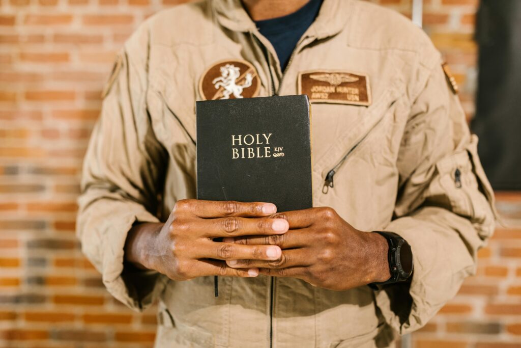 Military veteran in uniform holding the Holy Bible, symbolizing faith and spirituality.