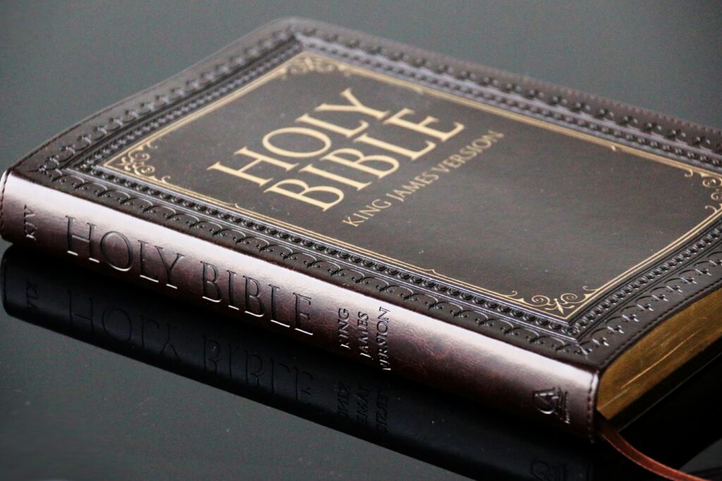 When the Pulpit Forgets the Pages: Why the Physical Bible Still Matters in a Screen-Saturated Age Close-up view of a leather bound King James Version Holy Bible resting on a reflective surface.